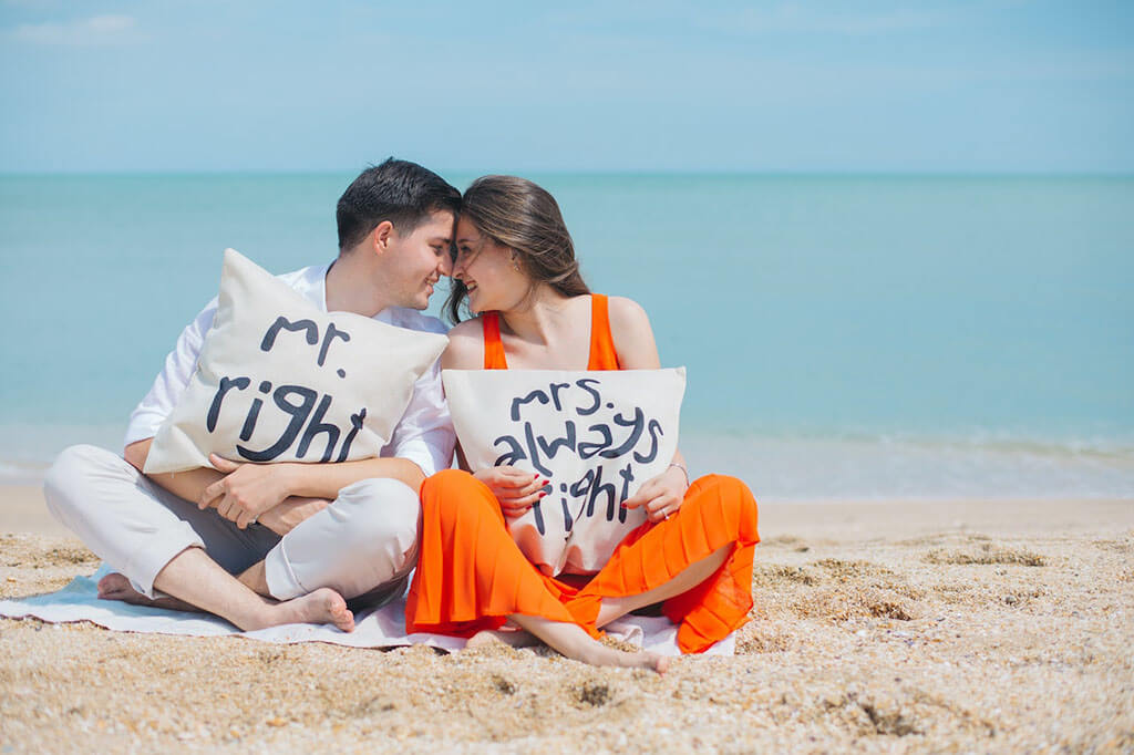 Man and Woman Wearing Cloths Sitting on Brown Sand